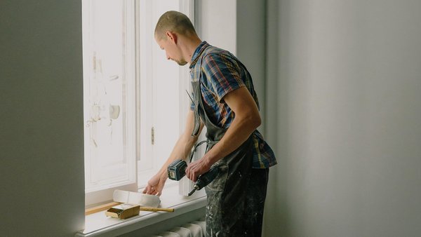 Omul repară o fereastră - asigurare privată de invaliditate profesională
