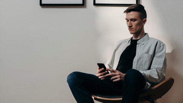 Bărbatul se uită nerăbdător la telefonul său mobil - creșterea prețurilor Bărbatul se uită nerăbdător la telefonul său mobil - creșterea prețurilor