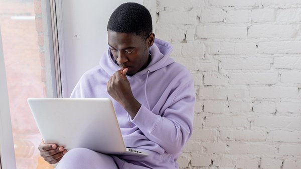 Studentull stă cugetând în fața unui laptop