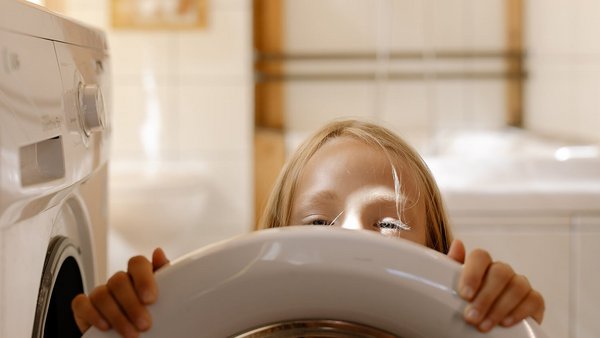 Fata în fața unei mașini de spălat - reduce costurile de energie