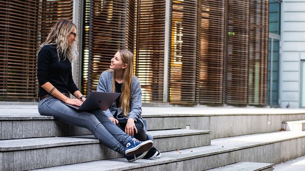 Studente care stau pe o scară râzând 