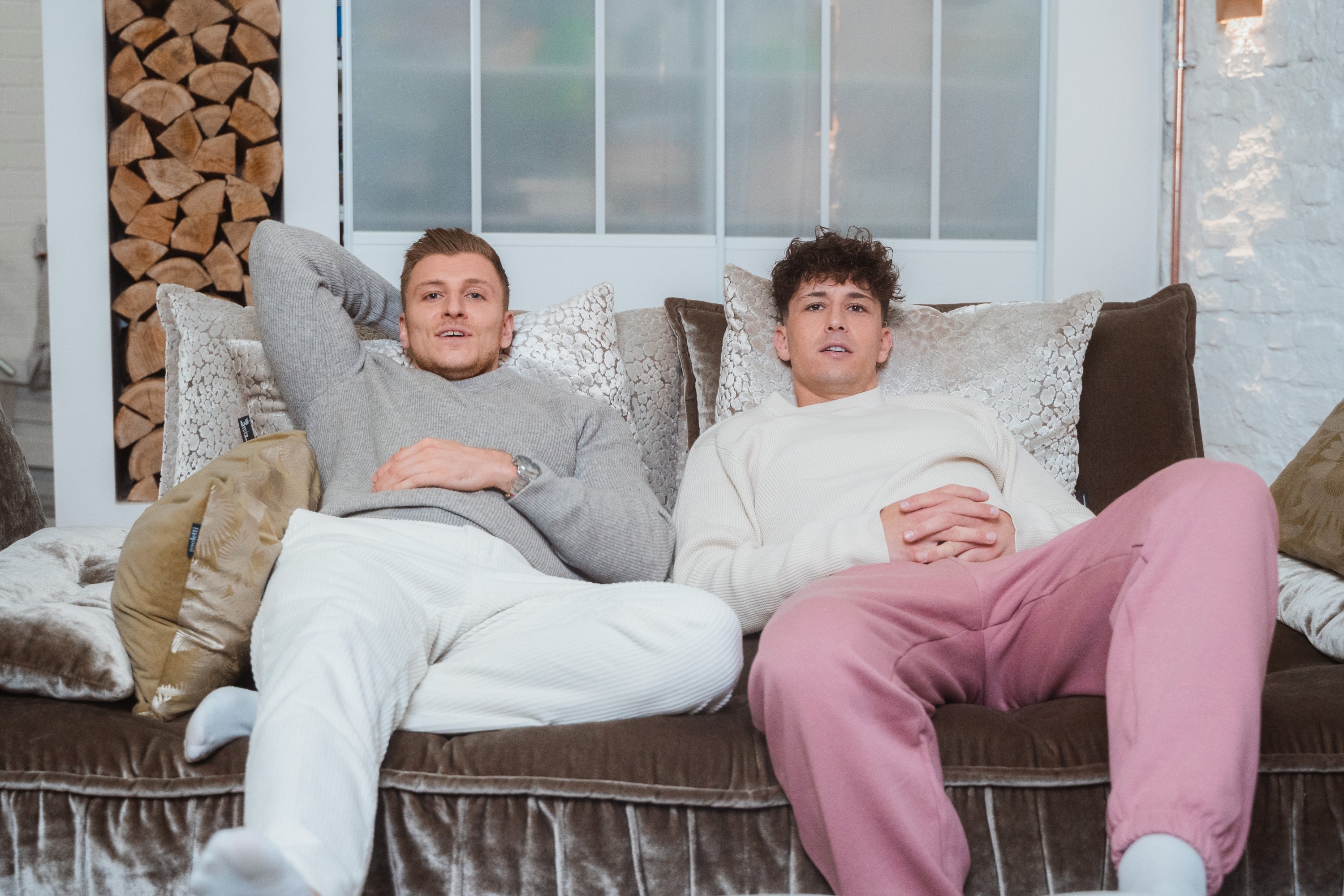 Zwei junge Männer sitzen auf dem Sofa.